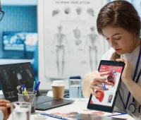 Médicos discutindo uma análise de imagem de um coração com um tablet em uma consulta médica, enfatizando tecnologia médica moderna.