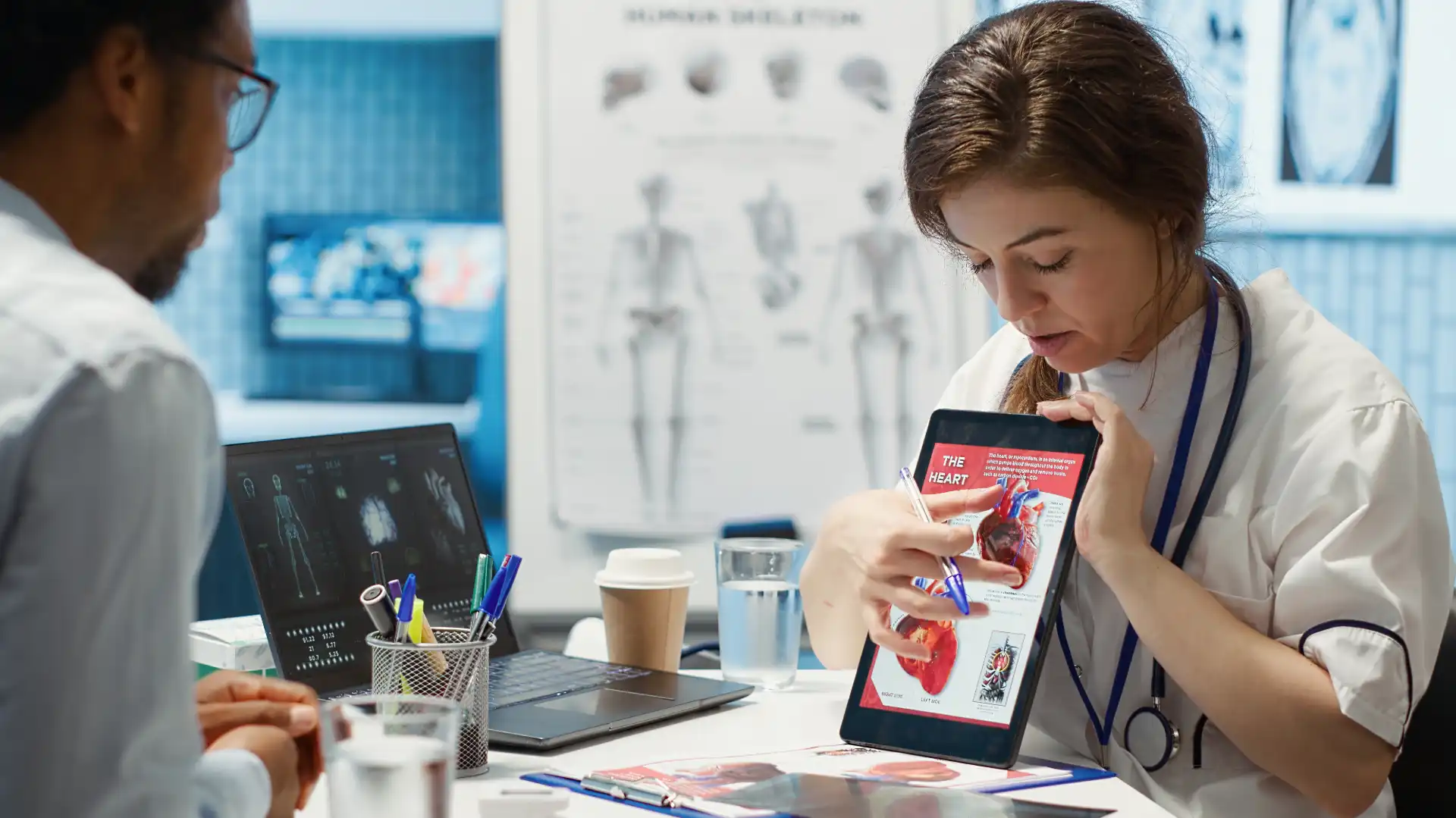 Médicos discutindo uma análise de imagem de um coração com um tablet em uma consulta médica, enfatizando tecnologia médica moderna.
