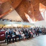 um grande grupo de pessoas sentadas em cadeiras em uma sala