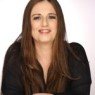 Foto da peofessora Andréa Carla de Moraes Pereira Lago. Mulher de cor branca e cabelos longos cobreados e olhos castanhos vestindo uma blusa de estilo formal na cor preto.