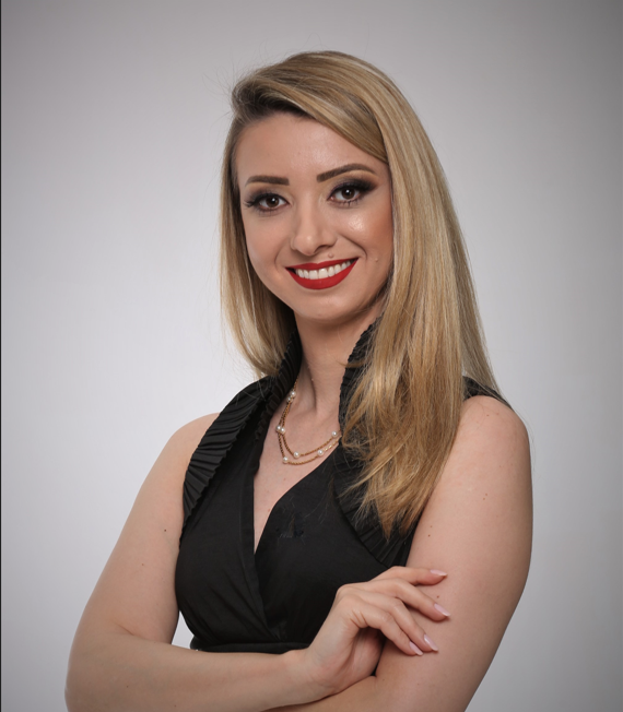 Foto da peofessora Andréa Carla de Moraes Pereira Lago. Mulher de cor branca e cabelos longos cobreados e olhos castanhos vestindo uma blusa de estilo formal na cor preto.