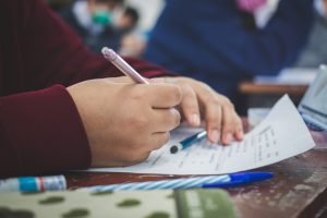 University,Student,Holding,Pen,Or,Pencil,Writing,On,Paper,Answer